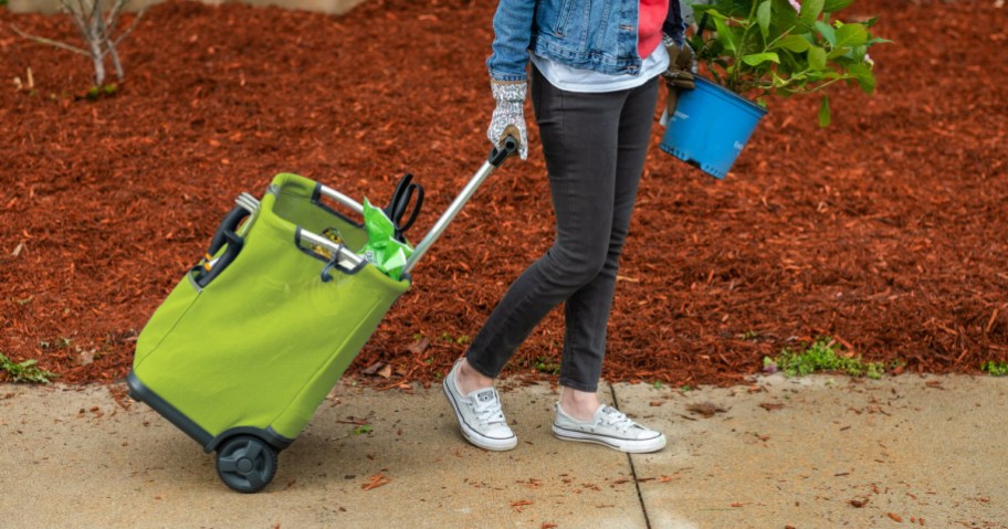 woman pulling a green gorilla folding cart behind her