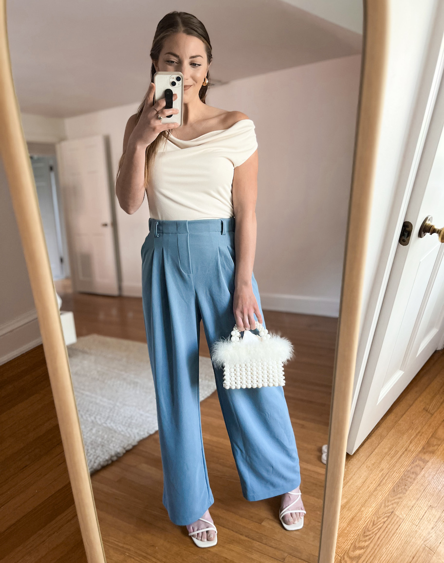 woman taking mirror selfie wearing blue pants white top and matching fluffy handbag