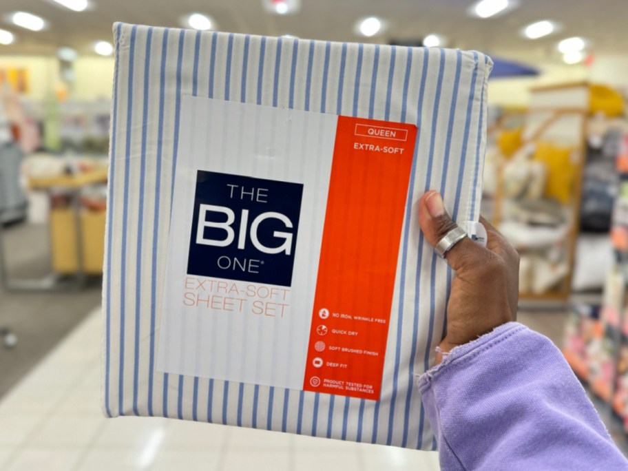 hand holding the big one sheet set in size queen at the store