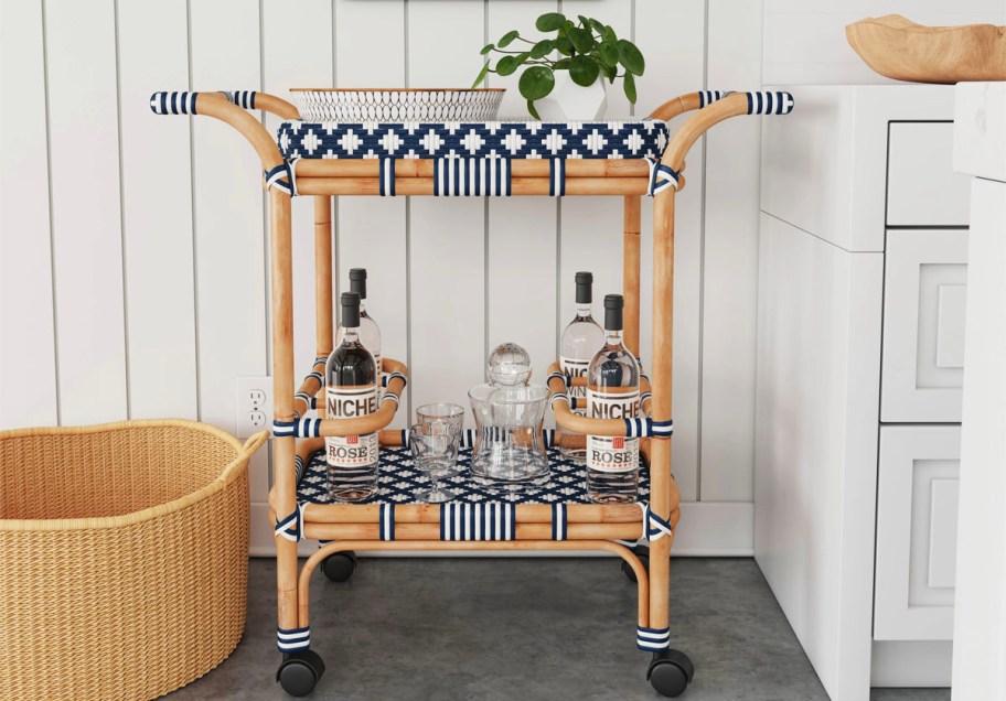 blue and white wood rattan bar cart with drinks on it 