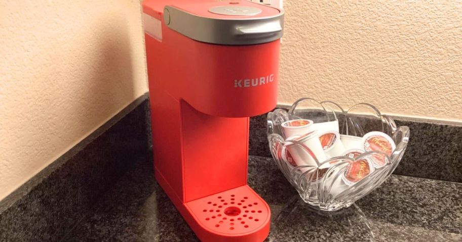 Keurig K-Mini Single Serve K-Cup Pod Coffee Maker in Poppy Red on counter next to bowl of sugar