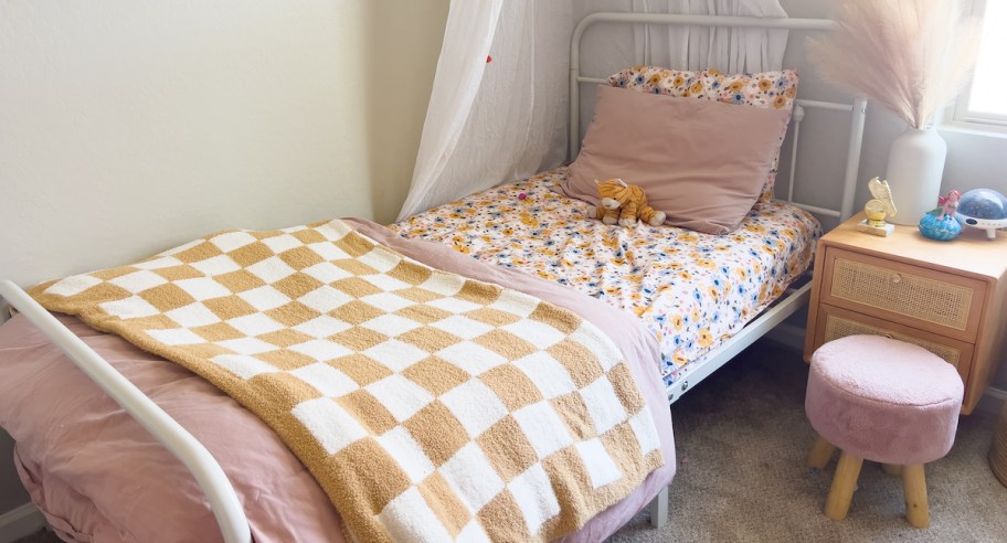 kids bed with checkered blanket and floral sheets