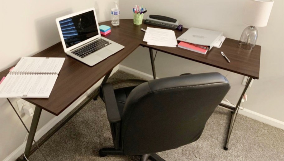 dark brown l shaped desk with laptop and other items on top