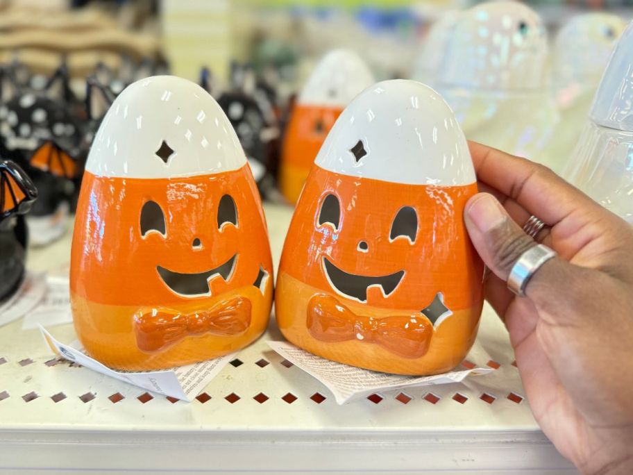 a womans hand holding a a ceramic light up candy corn jack o lantern