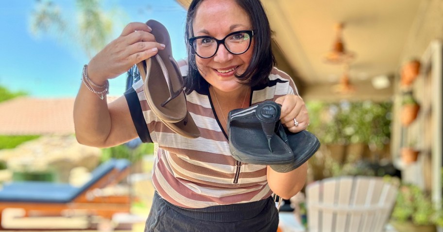 woman holding 2 pairs of flip flops