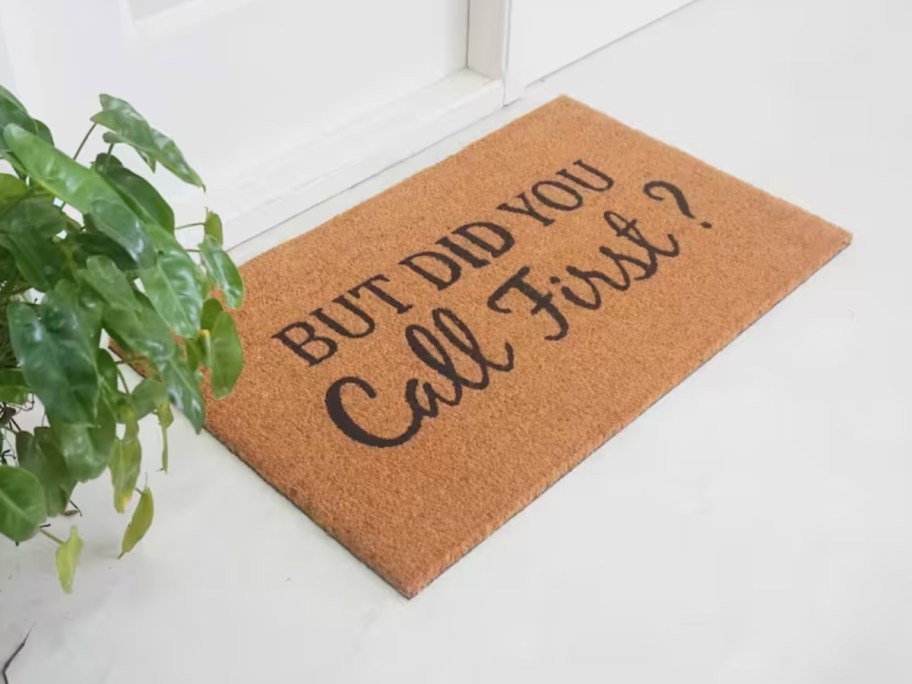 brown coir doormat that says "but did you call first" in front of a white door