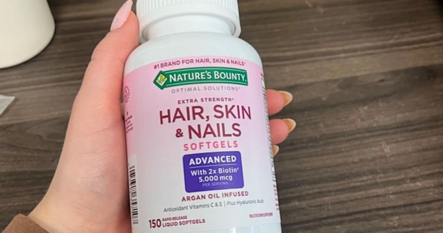 Hand holding a bottle of nature's Bounty Hair Skin and nails vitamins