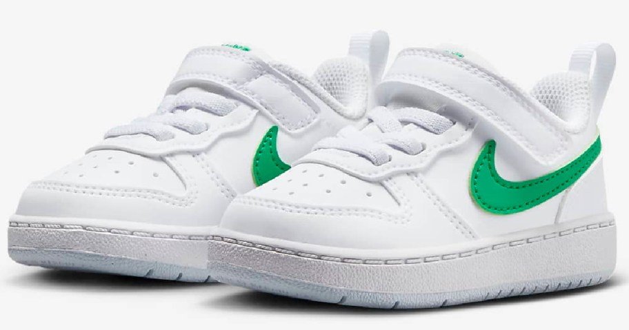 white nike court kids shoes with a green swoosh decal