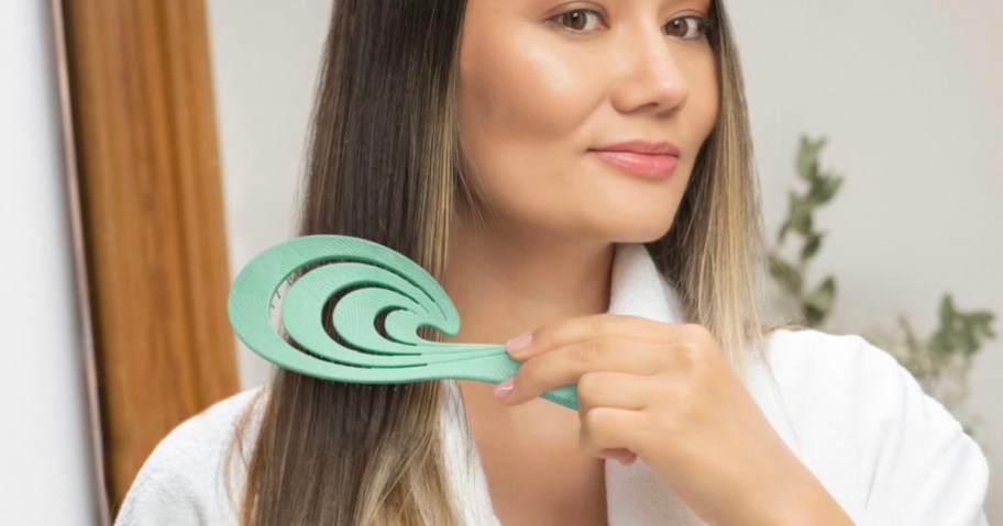 woman in white robe brushing hair with green brush