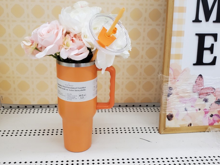 orange michaels tumbler filled with faux flowers sitting on a shelf