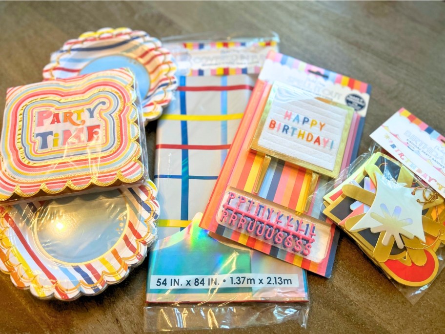 brightly colored birthday party plates, napkins, tablecloth, banner and cake decor