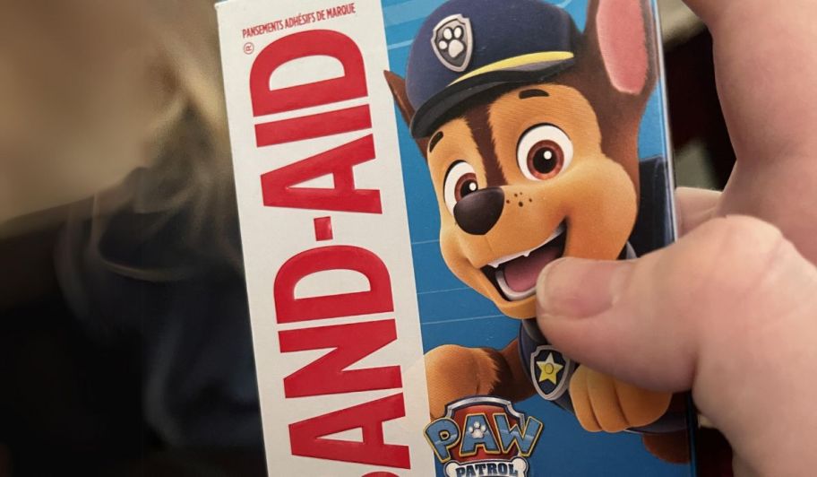 a mans hand holding a box of paw patrol band aids