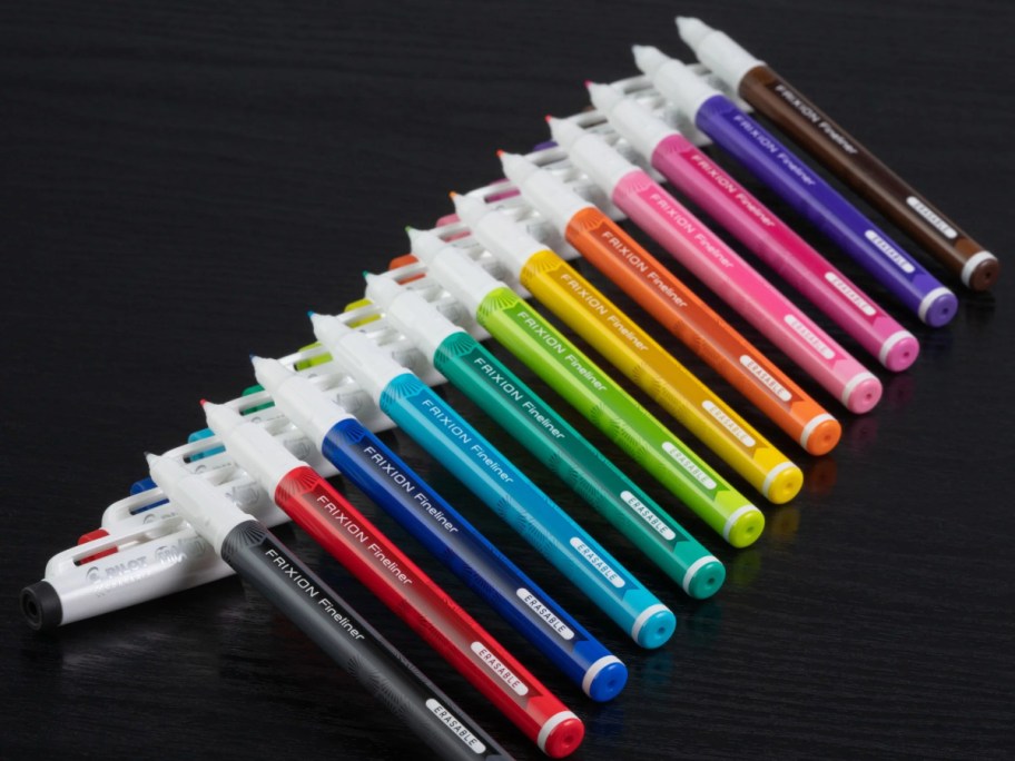 10 colorful markers lined up on a black table