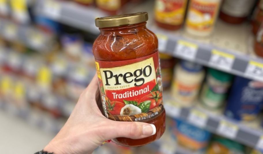 a womans hand holding a 24oz jar of prego traditional pasta sauce