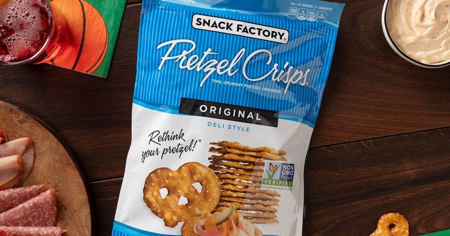 Snack Factory Original Pretzel Crisps, Non-GMO, 7.2 oz Resealable Bag laying on table next to drinks and appetizers