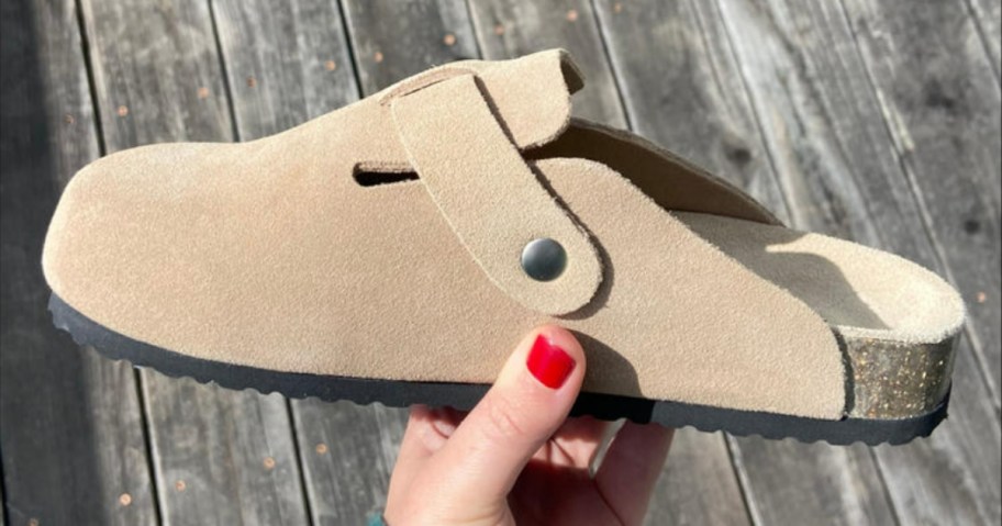 hand holding a light tan color suede mule clog