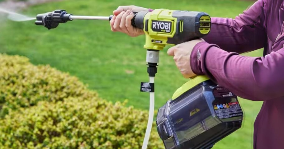 woman using a yellow Ryobi pressure washer to clean outside