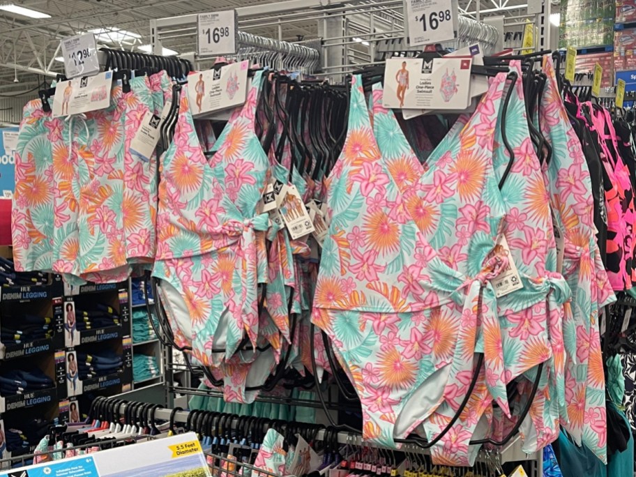 bright floral tropical men's swim trunks and women's swimsuits hanging on display at Sam's Club