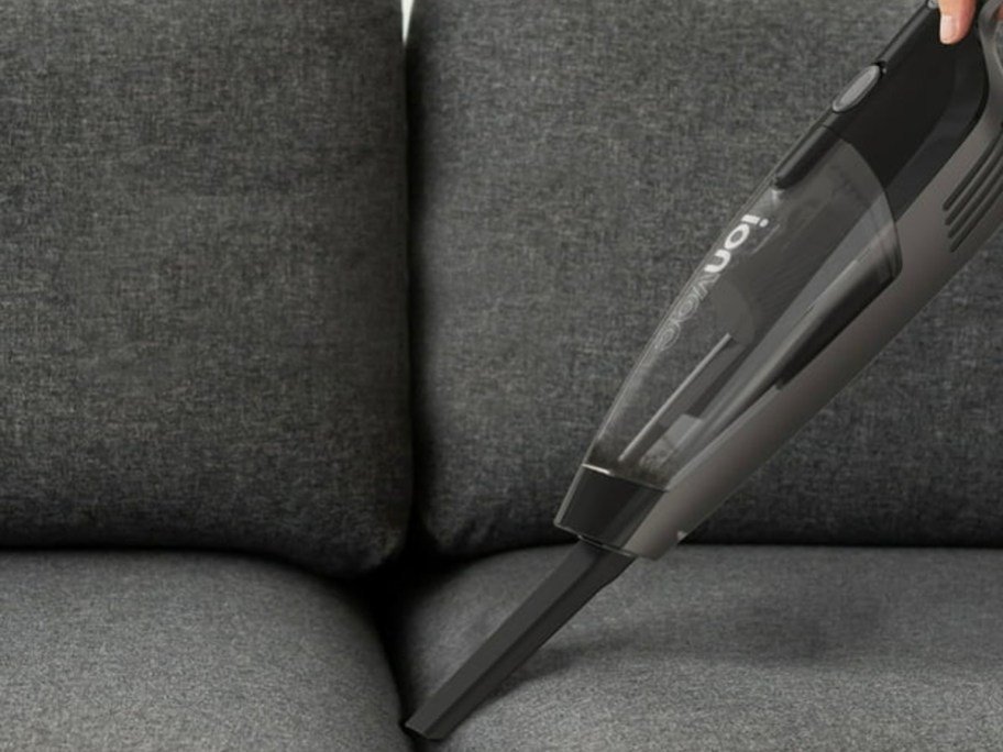 hand held vacuum cleaning dark gray couch
