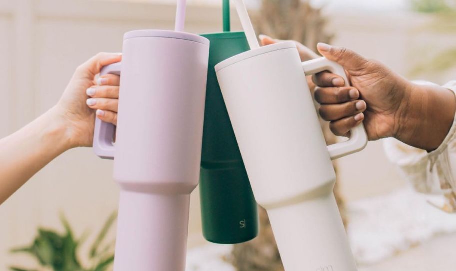 3 hands holding 40oz tumblers in a toast