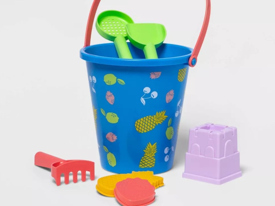 blue beach bucket with tropical designs on it surrounded by sand toys