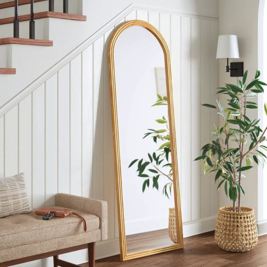 wood frame large arch wall mirror against a wall in an entryway