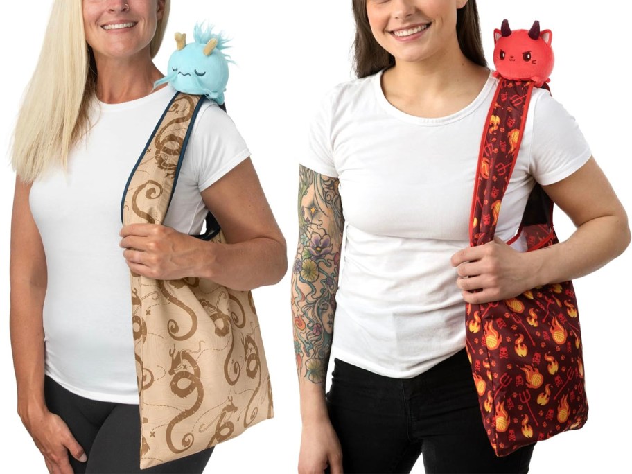 two women wearing blue dragon and red devil cat totes