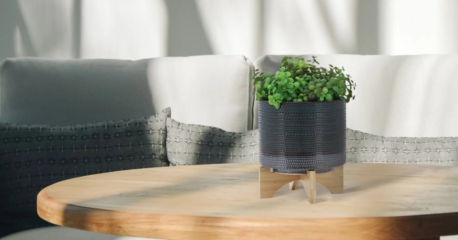 textured planter with stand sitting on a round table top