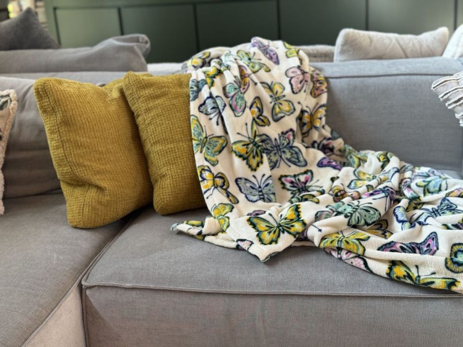 a butterfly throw blanket on a sofa next to a couple of throw pillows