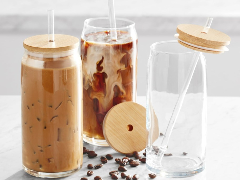 three glass containers with bamboo lids and straws