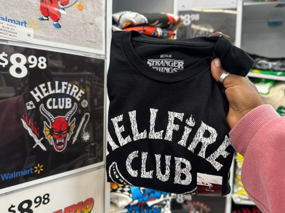hand holding a folded Stranger Things Hellfire Club t-shirt in store