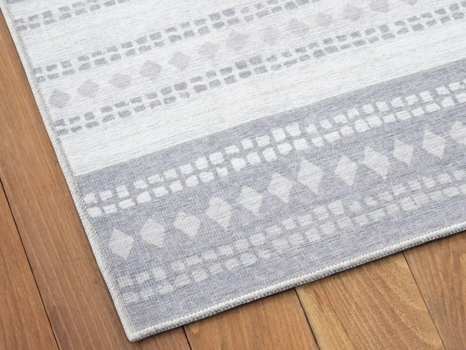 corner of a light grey and white stripe geometric pattern floor rug on a floor