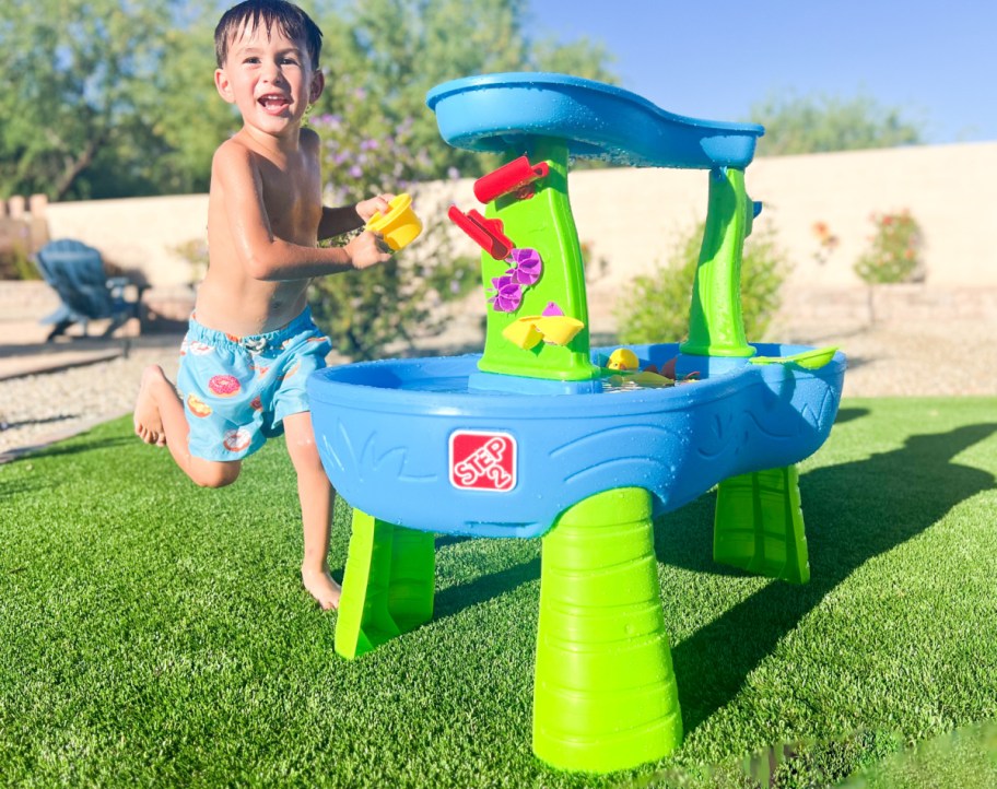boy playing with water table outside