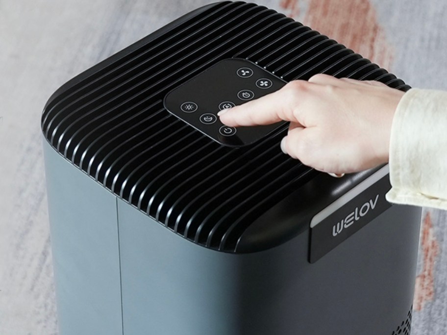 hand pushing buttons on air purifier 