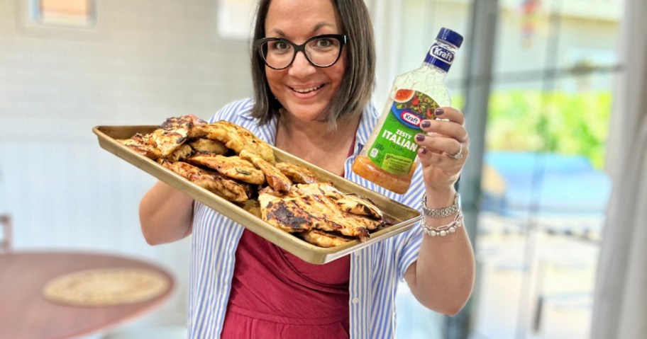 woman holding a pan of grilled chicken and salad dressing