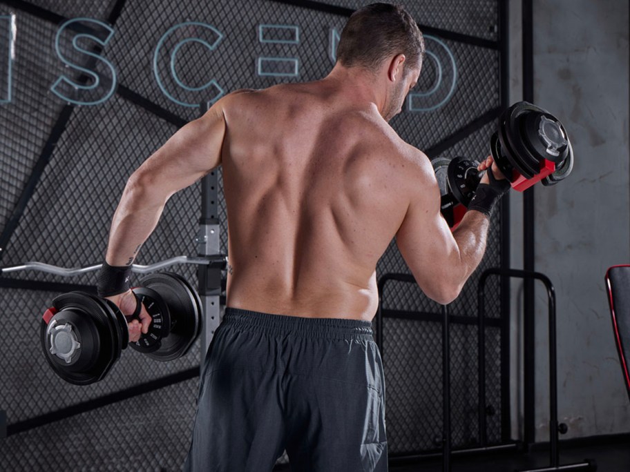 man holding two dumbbells in gym