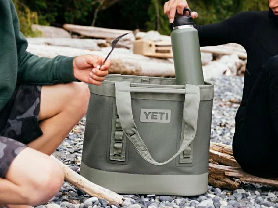 two people sitting next to yeti green tote and water bottle