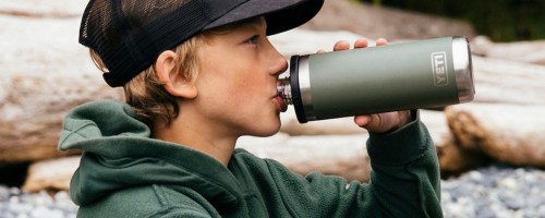 kid in black hat drinking of of a green yeti water bottle