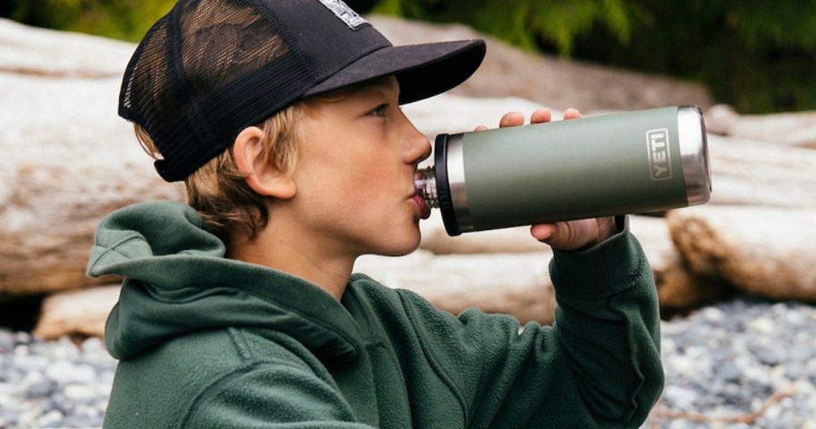kid in black hat drinking of of a green yeti water bottle 
