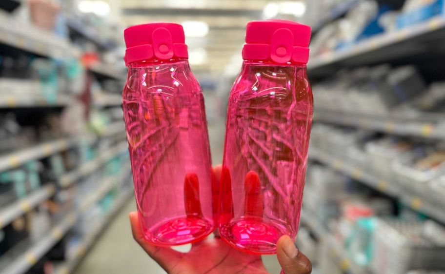 a womans hand holding 2 pink your zone waterbottles