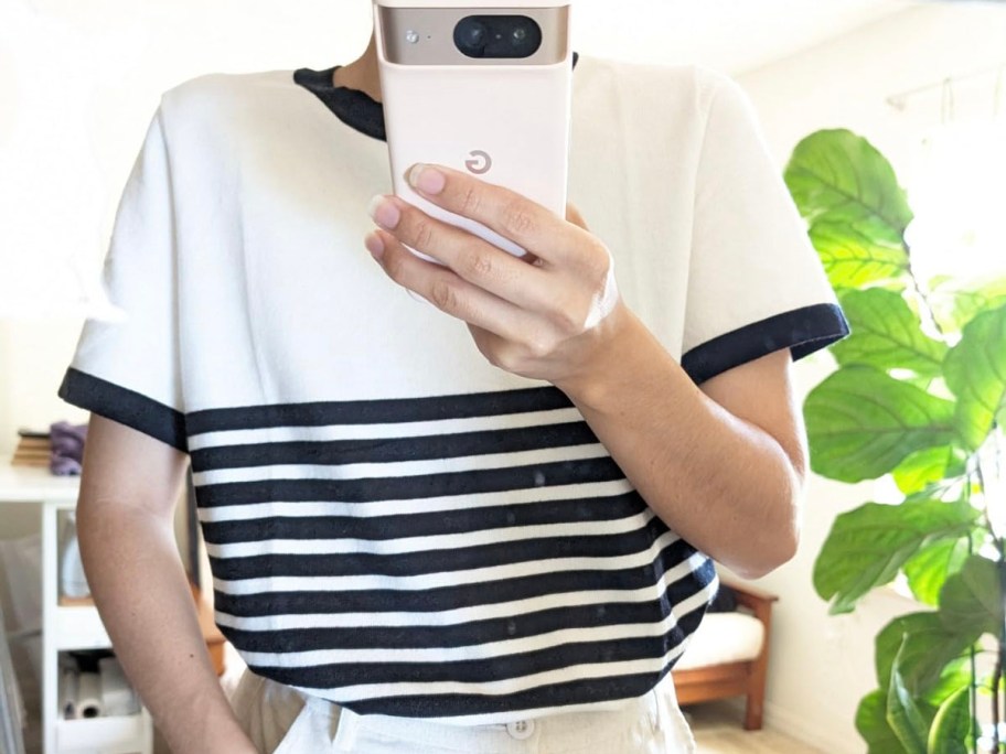 woman wearing white and black striped tee taking pic holding phone