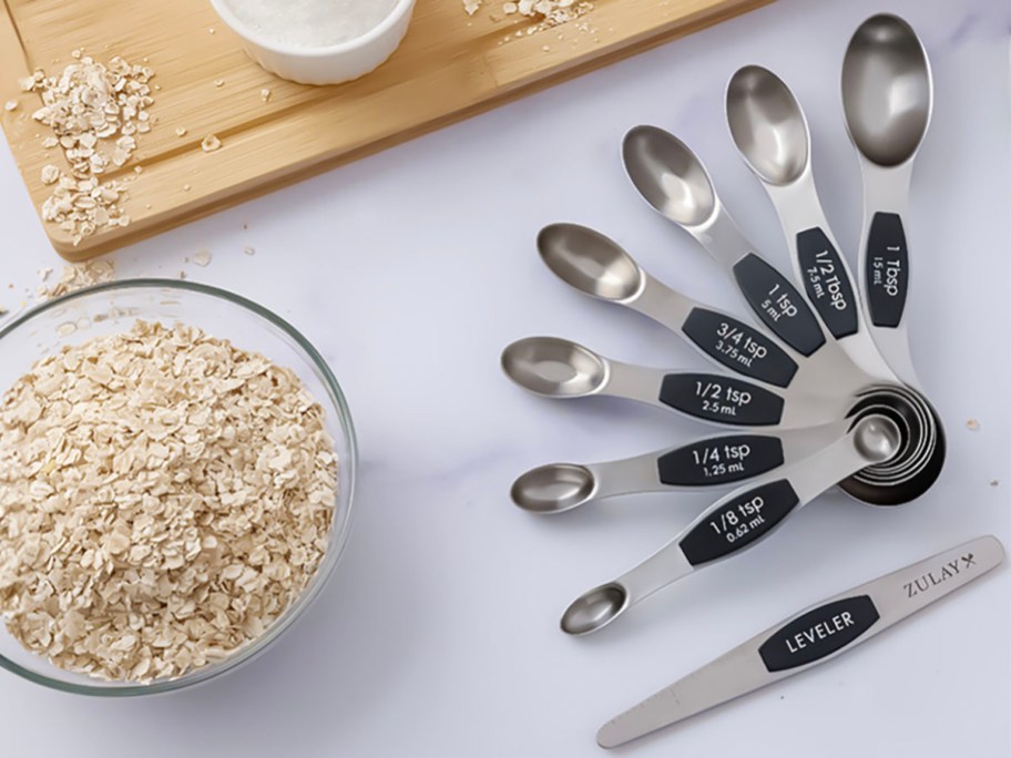 measuring spoons laying in a circle next to bowl of granola