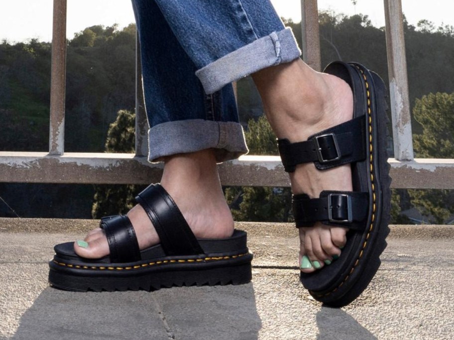 women's feet wearing black double buckle Dr. Martens sandals