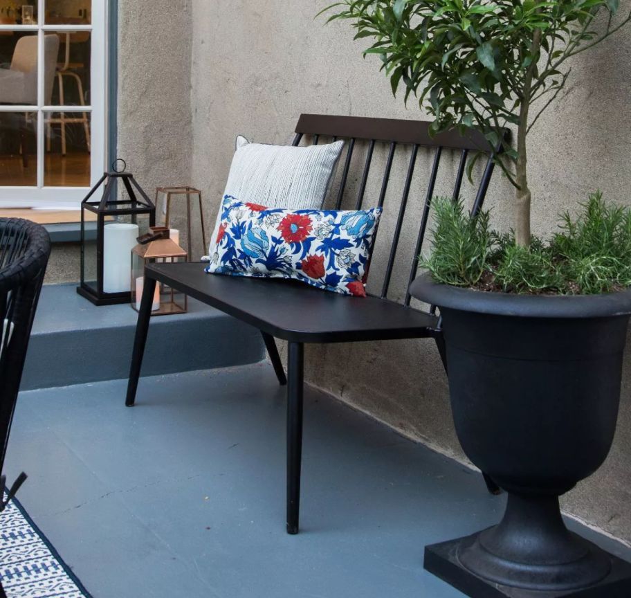 a metal bench with floral throw pillows on a patio