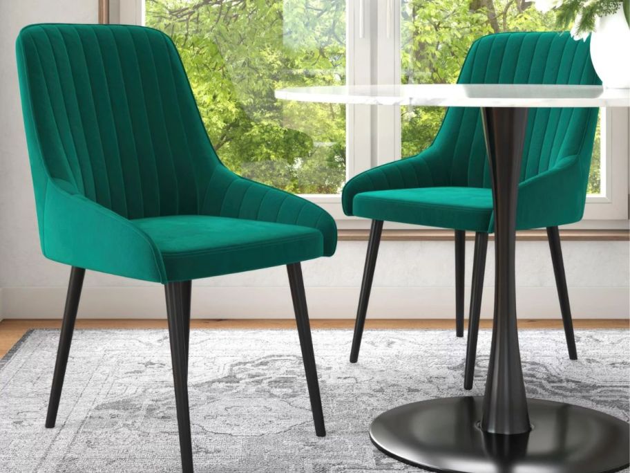 set of green velvet dining chairs next to a dining table