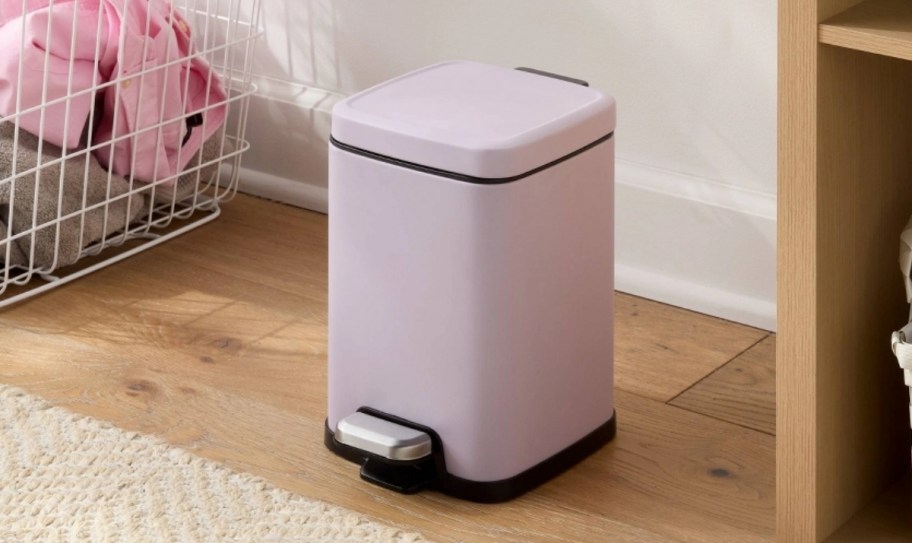 a small lavender colored step trash can