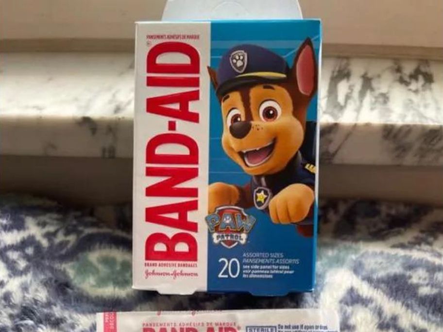Band-Aid Bandages - PAW Patrol Characters Assorted Sizes 20-Count box on counter with a single band aid in front of it