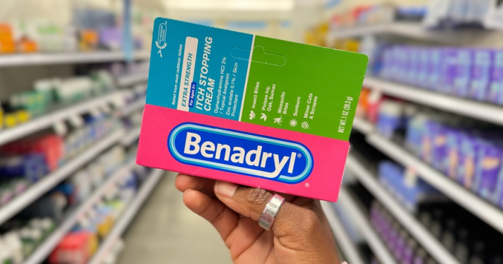 person holding up box of Benadryl Itch Cream in store aisle