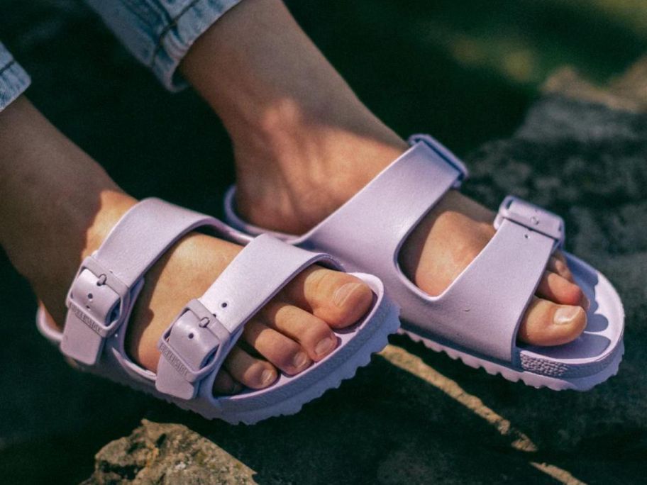 A woman wearing a pair of Birkenstock Arizona Eva Sandals in Purple Fog  