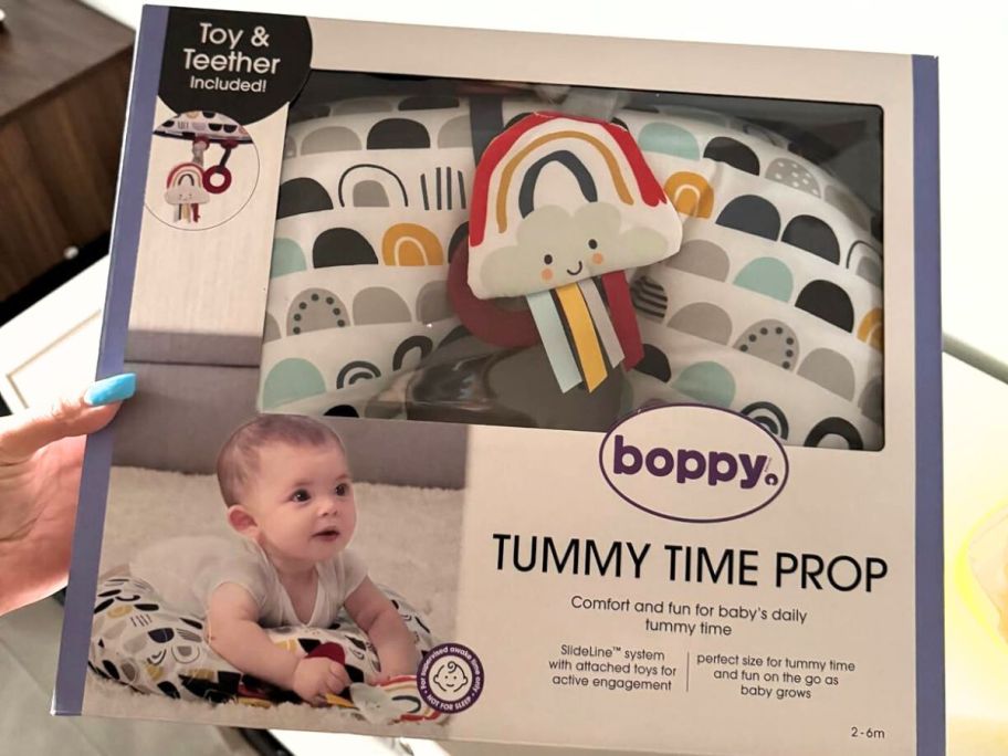 Hand holding up a Boppy Tummy Time Prop brand new in the box